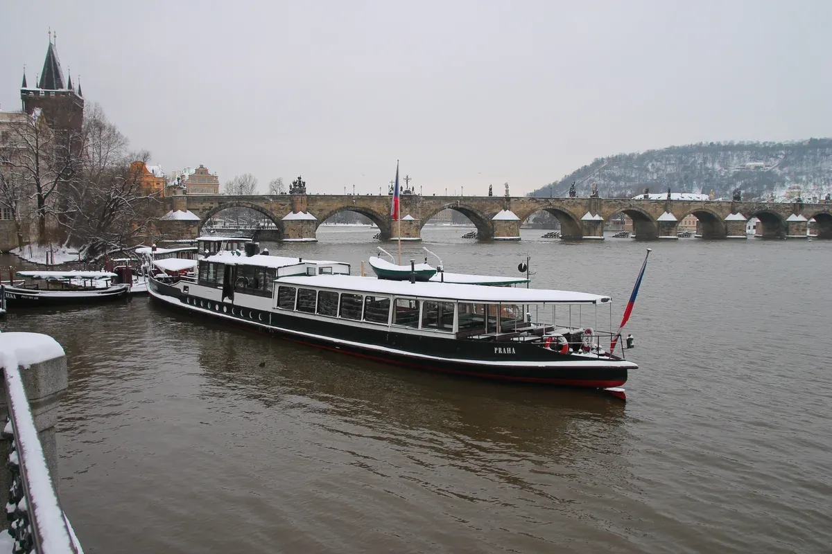 Snow on the riverbank and Charles Bridge on a grey day, typical Prague weather in December